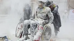 Seorang peserta menggunakan kursi roda saat mengikuti Festival Els Enfarinats di kota Ibi, Spanyol, Rabu (28/12). Dalam festival ini para peserta diharuskan memakai pakaian yang menyerupai kostum perang/militer. (AFP PHOTO / Jamie Reina)