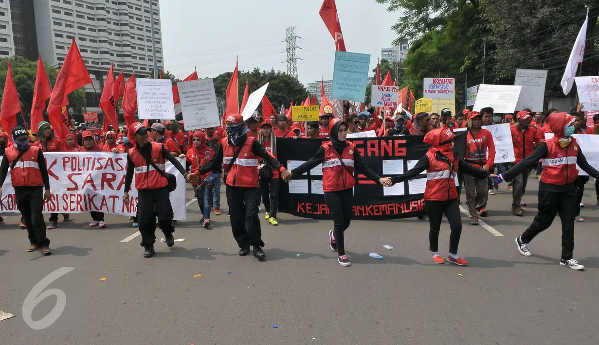 Massa buruh berjalan menuju Istana Negara saat aksi Hari Buruh di Jakarta, Senin (1/5). Dalam aksinya para buruh meminta sistem kerja kontrak dan upah rendah dihapus. (Liputan6.com/Helmi Afandi)