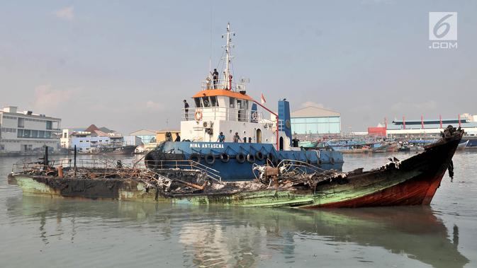 Petugas menggunakan kapal tongkang saat mengevakuasi sebuah kapal yang disebut titik awal kebakaran di Pelabuhan Muara Baru, Jakarta, Minggu (24/2). (Merdeka.com/Iqbal Nugroho)