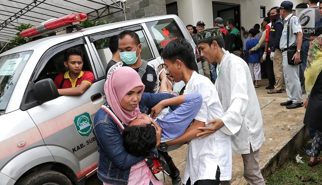 Salah seorang keluarga pingsan sambut kedatangan jenazah kecelakaan Tanjakan Emen Kabupaten Subang di RSUD Tangsel, Ciputat, Minggu (11/2). Diduga, bus mengalami rem blong saat menuruni Tanjakan Emen. (Liputan6.com/Fery Pradolo)