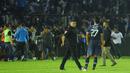 Pemain, ofisial, dan perangkat pertandingan laga Arema Vs Persebaya diberikan kawalan ketat untuk masuk ke dalam ruang stadion karena mereka tak henti-hentinya dilempari botol dan benda-benda lainnya dari tribun Stadion Kanjuruhan, Malang, pada Sabtu (1/10/2022) malam. (Bola.com/Iwan Setiawan)