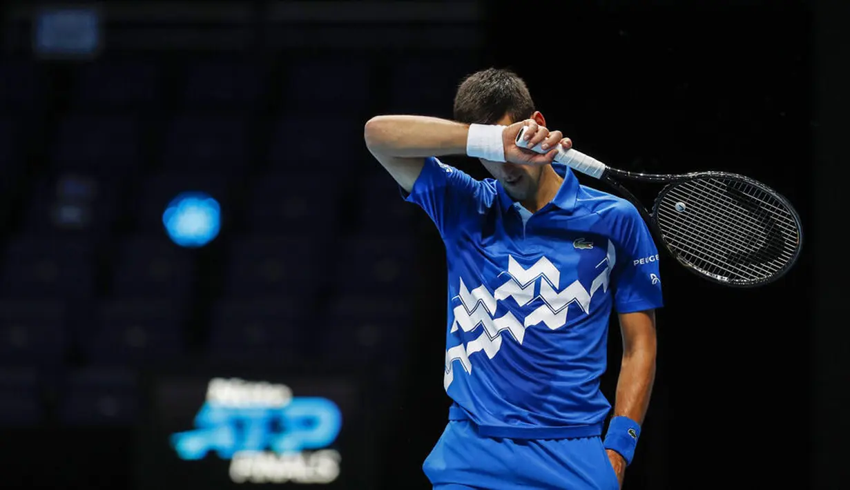 Petenis Serbia, Novak Djokovic, menutup wajahnya dengan tangan usai ditaklukkan Petenis Rusia, Daniil Medvedev, pada ATP Finals di O2 Arena, London, Kamis (19/11/2020). Petenis nomor satu dunia itu takluk 3-6 3-6. (AP/Frank Augstein)