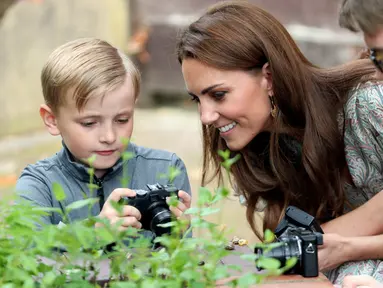 Duchess of Cambridge Kate Middleton melihat hasil foto seorang anak saat ikut serta belajar fotografi dengan Action for Children di Kingston upon Thames, Inggris (25/6/2019). (AFP Photo/Chris Jackson)