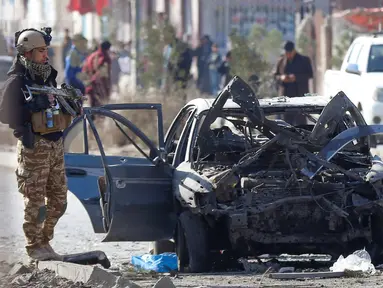 Seorang tentara berdiri di samping kendaraan yang rusak setelah serangan bom mobil di Kabul, Afghanistan (13/11/2019). Setidaknya tujuh orang tewas dan tujuh lainnya luka-luka ketika sebuah bom mobil meledak pada jam sibuk pagi hari Kabul pada 13 November. (AFP/STR)