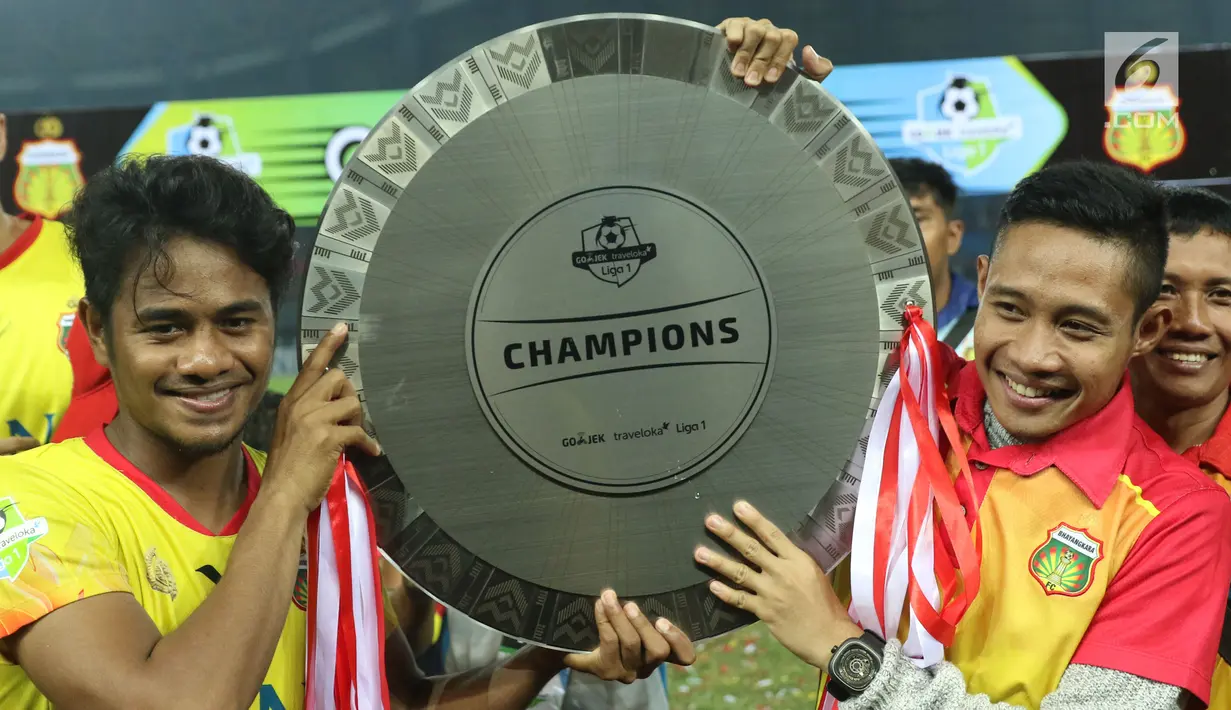 Pemain Bhayangkara FC, Evan Dimas (kanan) bersama Ilham Udin Armaiyn mengangkat piala Liga 1 Indonesia usai melawan Persija di Stadion Patriot Candrabhaga, Bekasi, Minggu (12/11). (Liputan6.com/Helmi Fithriansyah)