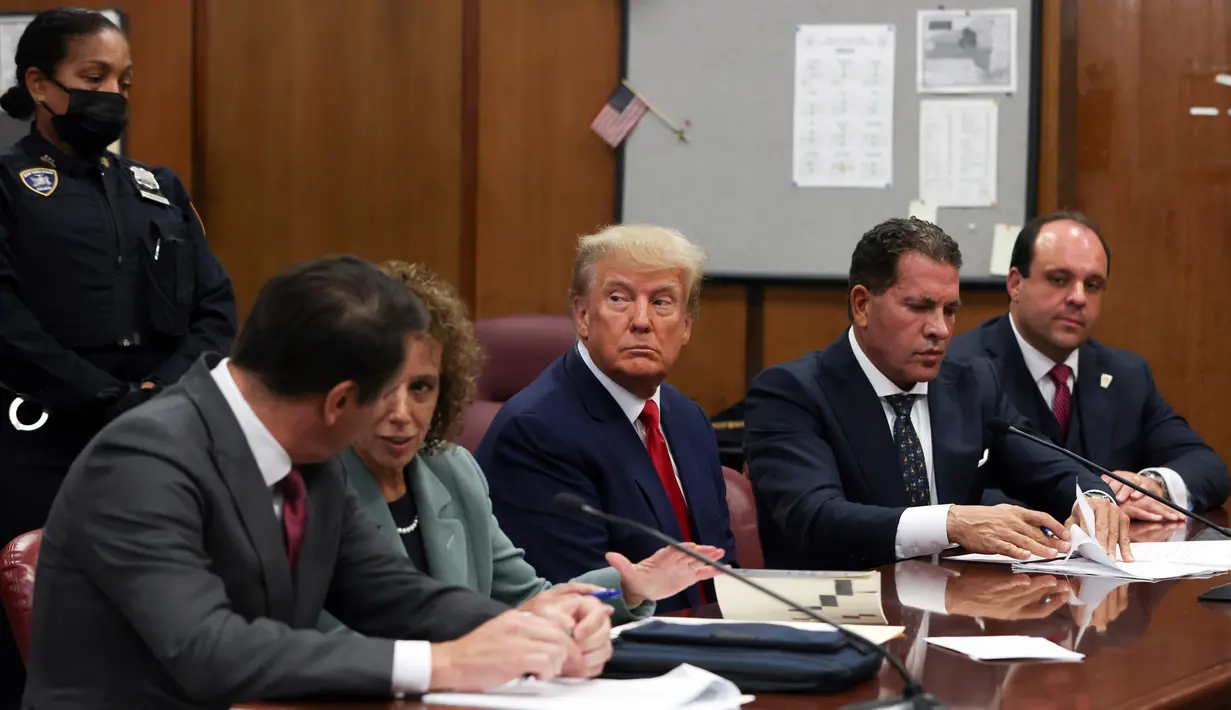 <p>Foto-foto yang beredar menunjukkan, Trump duduk di meja terdakwa dengan diapit pengacaranya Joe Tacopina dan Susan Necheles. Sementara petugas polisi Kota New York berjaga di belakangnya. (Andrew Kelly/Pool Photo via AP)</p>