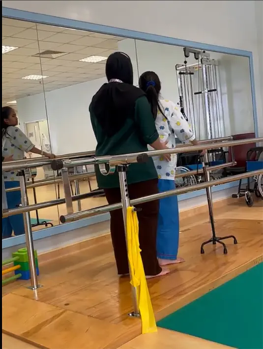 Kondisi terus membaik dan tak lagi memakai pampers. "Alhamdulillah, gambar Puteri sedang membuat sesi fisio. Puteri sudah boleh berdiri & berjalan dengan bantuan tongkat. Sakit juga sudah makin berkurangan. Puteri juga sudah tidak lagi memakai pampers." tulis puterirafasya1. [Instagram/puterirafasya1]