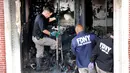 Petugas pemadam kebakaran memeriksa apartemen yang terbakar di kawasan Harlem, New York, Amerika Serikat, Rabu (8/5/2019). Bangunan yang terbakar merupakan kompleks apartemen yang dikelola oleh pemerintah kota. (AP Photo/Richard Drew)