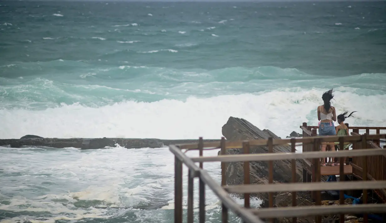 Orang-orang menyaksikan ombak di sepanjang pantai timur laut di New Taipei City saat Topan Hinnamnor mendekati Taiwan timur (3/9/2022). Badai itu membawa angin berkelanjutan maksimum 173 kilometer per jam, dengan hembusan hingga 209 kilometer per jam. (AFP/Sam Yeh)