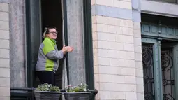 Seorang wanita bertepuk tangan dari jendela untuk menunjukkan penghormatan terhadap orang-orang yang bertugas di garis depan melawan pandemi virus corona COVID-19 di Brussel, Belgia,Selasa (14/4/2020). Kasus COVID-19 di Belgia sebanyak 31.119 positif dan 4.157 meninggal. (Xinhua/Zhang Cheng)