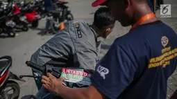 Pekerja menempelkan stiker pada motor pemudik sebelum dikirim dengan kereta api di Stasiun Jakarta Gudang, Selasa (28/5/2019). Direktorat Lalu Lintas dan Angkutan Kereta Api Kementerian Perhubungan mengangkut 18.096 motor pemudik secara gratis pada mudik Lebaran 2019. (Liputan6.com/Faizal Fanani)