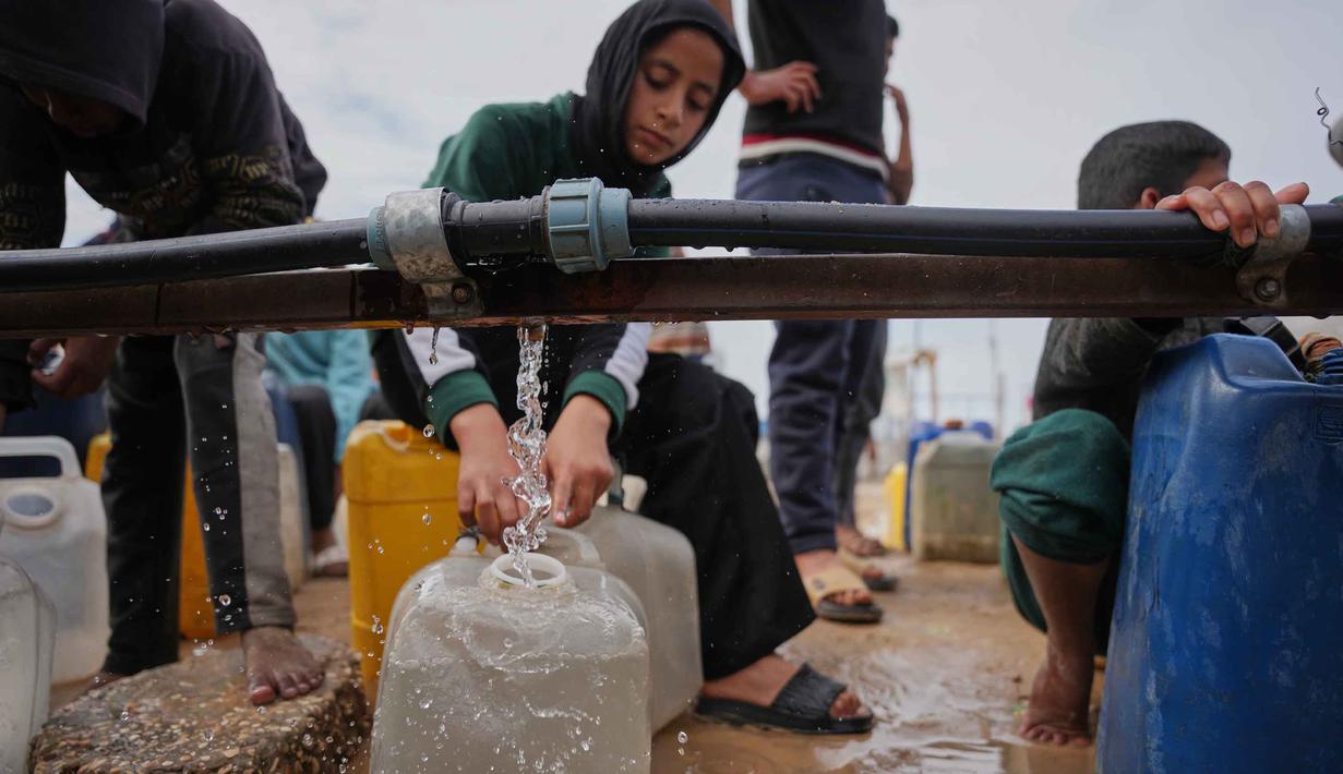 Seorang pemuda Palestina mengambil air di pabrik desalinasi, Khan Younis, Jalur Gaza selatan, Jumat 6 Februari 2026. Pengungsi Palestina di Gaza masih harus berjuang untuk mendapatkan air bersih dan bantuan makanan di dapur umum Khan Younis, Jalur Gaza selatan. (AP Photo/Abdel Kareem Hana)
