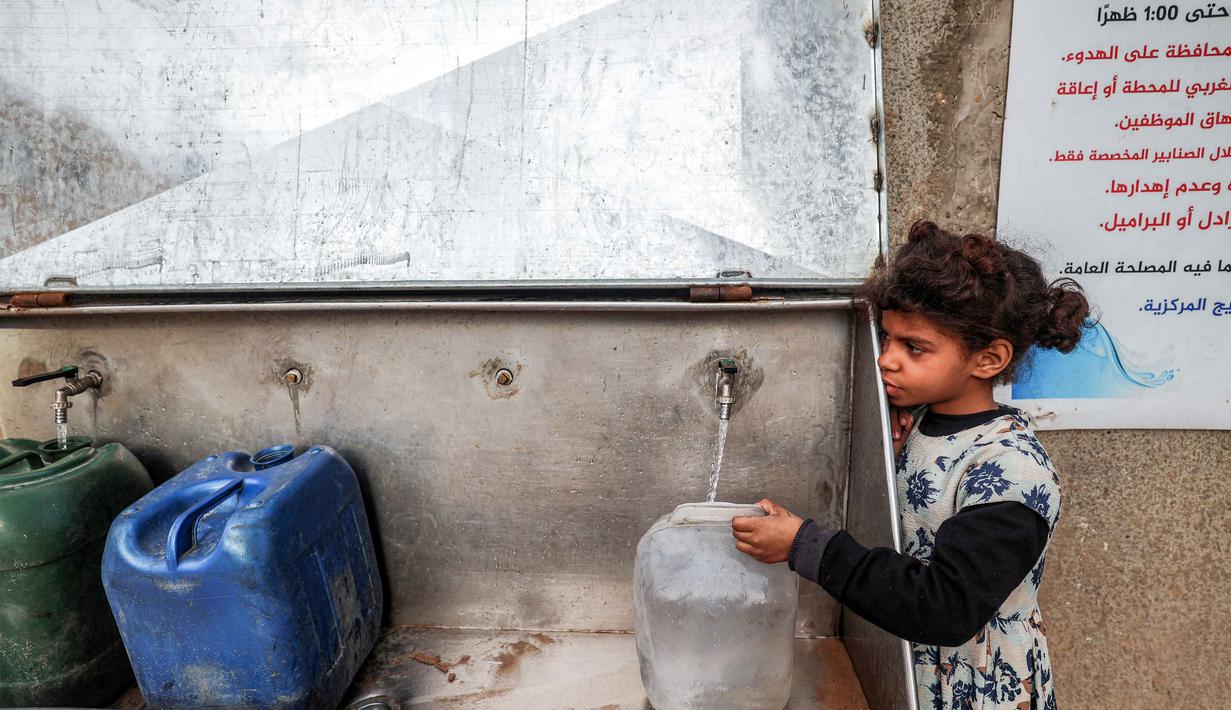 Untuk diketahui, hingga akhir Januari 2026, kondisi infrastruktur dan akses pendidikan di Gaza berada pada titik kritis, sekitar 90% hingga 98% bangunan sekolah mengalami kerusakan mulai dari tingkat parsial hingga hancur total. Tampak dalam foto, seorang gadis kecil mengisi wadah dengan air dari sumur umum, di kamp pengungsi Palestina Nuseirat di utara Deir al-Balah, Jalur Gaza tengah pada 29 Januari 2026. (EYAD BABA/AFP)