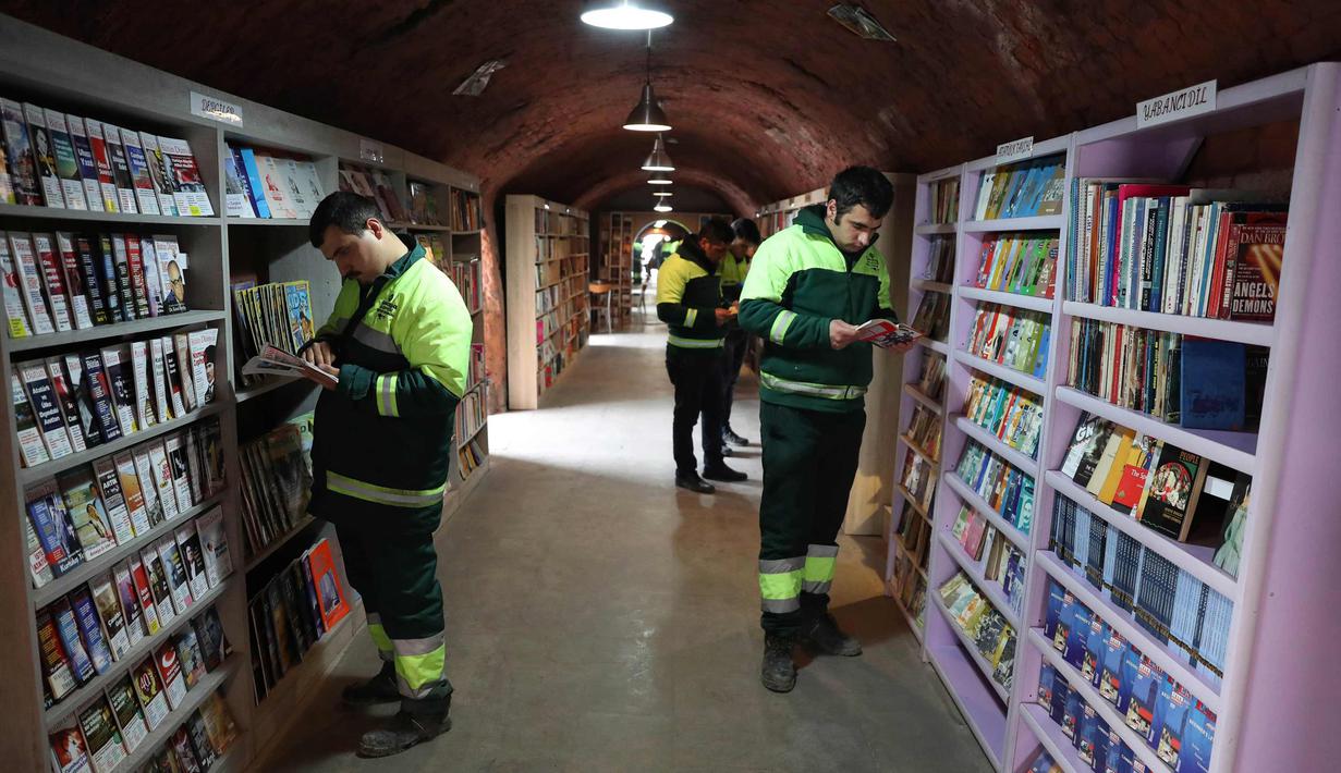 Petugas kebersihan membaca buku di perpustakan tempat mereka bekerja di distrik Cankaya, Ankara, Turki (9/1).Beberapa petugas ini membuat band bernama "Grup Tin", dengan menggunakan tempat sampah dan barang bekas sebagai alat musik. (AFP Photo/Adem Altan)