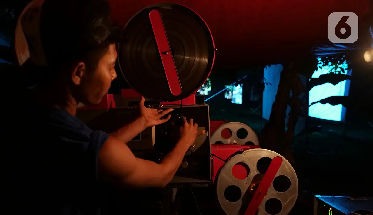 Teknisi memasukan film ke proyektor film layar tancap di kawasan Sawangan, Depok, Jawa Barat, Sabtu (11/7/2020). Layar tancap atau bioskop terbuka menjadi alternatif bagi warga untuk menikmati film di tengah penerapan new normal di kawasan Jabodetabek. (Liputan6.com/Herman Zakharia)