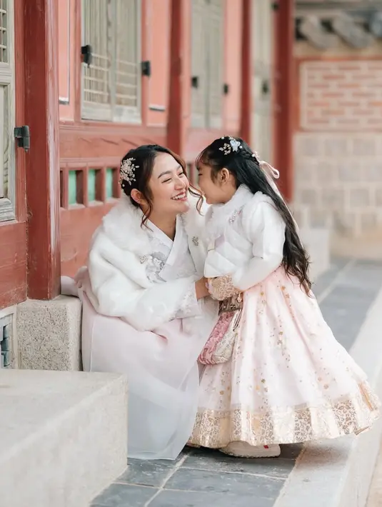 Putrinya tampil mengenakan hanbok warna atasan putih dengan rok soft pink bermotif gold. [@sitibadriahh]