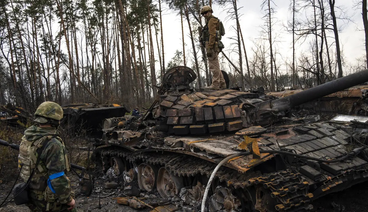 Seorang tentara Ukraina berdiri di atas tank Rusia yang hancur di pinggiran Kiev, Ukraina, 31 Maret 2022. Pasukan Rusia menembaki pinggiran Kota Kiev, dua hari setelah Kremlin mengumumkan akan secara signifikan mengurangi operasi dekat Ibu Kota dan Chernihiv. (AP Photo/Rodrigo Abd)