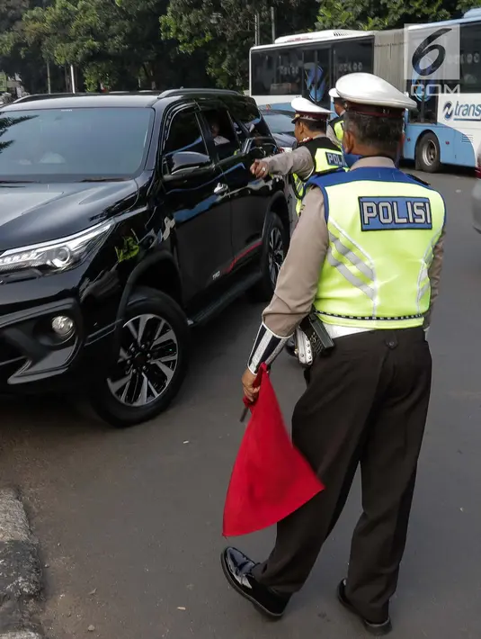 Petugas polisi lalu lintas memberi arahan kepada pengguna mobil saat pemberlakuan sistem ganjil genap di pintu masuk Gardu Tol Cibubur 2, Jakarta, Senin (16/4). (Liputan6.com/Faizal Fanani)