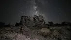 Seorang pria memandangi Galaksi Bima Sakti yang menghiasi langit malam saat dia duduk di antara reruntuhan bangunan akibat pengeboman di Kota Ariha, Provinsi Idlib, Suriah, Sabtu (27/6/2020). (Omar HAJ KADOUR/AFP)