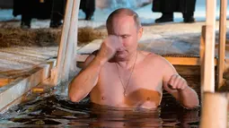 Vladimir Putin berendam di air dingin di Danau Seliger di desa Svetlitsa, Rusia (19/1). Ritual ini dianggap umat Kristen Ortodoks untuk membersihkan diri dari dosa yang dilakukan setahun terakhir. (Alexei Druzhinin, Sputnik, Kremlin Pool Photo via AP)