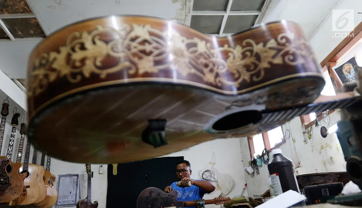 Pekerja tengah mengukir gitar di workshop I Wayan Tuges  gitar berlabel Blueberry di Jalan Baruna No. 5 Guwang, Sukowati, Bali, Senin (15/10). Gitar-gitar produksinya itu dibanderol seharga puluhan juta rupiah. (Liputan6.com/Angga Yuniar)
