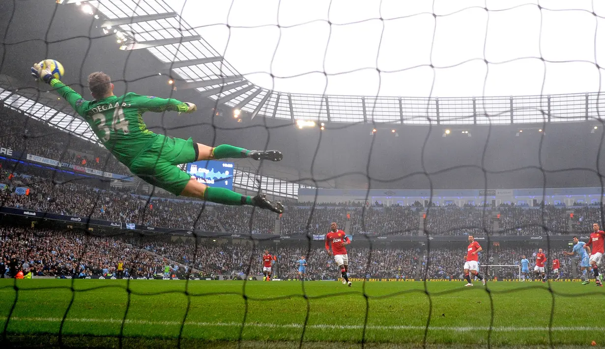 Kiper Manchester United, Anders Lindegaard berusaha menghalau bola tendangan pemain Manchester City, Sergio Aguero pada laga putaran ketiga Piala FA 2011/2012 yang berlangsung di Etihad Stadium, Manchester, 8 Januari 2012. Setan Merah menang dengan skor 3-2. (AFP/Andrew Yates)