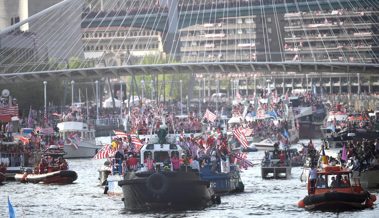 Pemain Athletic Bilbao bersama suporter melakukan pawai perayaan juara Copa del Rey dengan menyusuri Sungai Nervion, Bilbao, Jumat (12/4/2024). Trofi Copa Del Rey diarak menyusuri Sungai Nervion dengan perahu, yang disambut meriah oleh ratusan ribu orang. (AFP/Ander Gillenea)