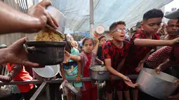 Beberapa anak antre untuk mendapatkan makanan dari dapur amal di kamp pengungsi Nuseirat, yang terletak di bagian tengah Jalur Gaza, pada 21 Oktober 2025. (Eyad BABA/AFP)