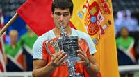 Petenis Spanyol Carlos Alcaraz&nbsp;berselebrasi dengan trofinya&nbsp;usai mengalahkan Casper Ruud dari Norwegia dalam pertandingan final tunggal putra&nbsp;US Open 2022 di USTA Billie Jean King National Tennis Center, New York, pada pada Senin (12/9/2022) pagi WIB. (ANGELA WEISS / AFP)
