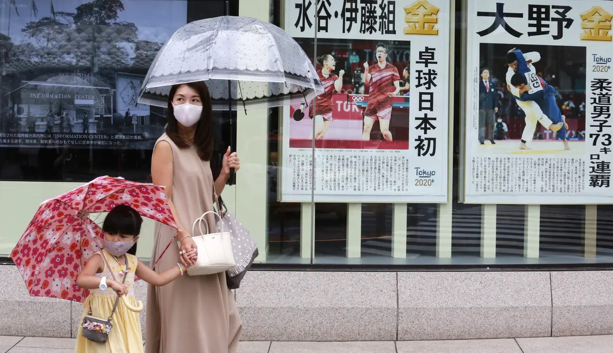 Warga yang mengenakan masker untuk melindungi diri dari penyebaran COVID-19 berjalan melewati laporan raihan medali emas Jepang di Olimpiade Tokyo 2020, Tokyo, Selasa (27/7/2021). Tokyo melaporkan jumlah kasus harian COVID-19 tertinggi beberapa hari setelah Olimpiade mulai. (AP Photo/Koji Sasahara)