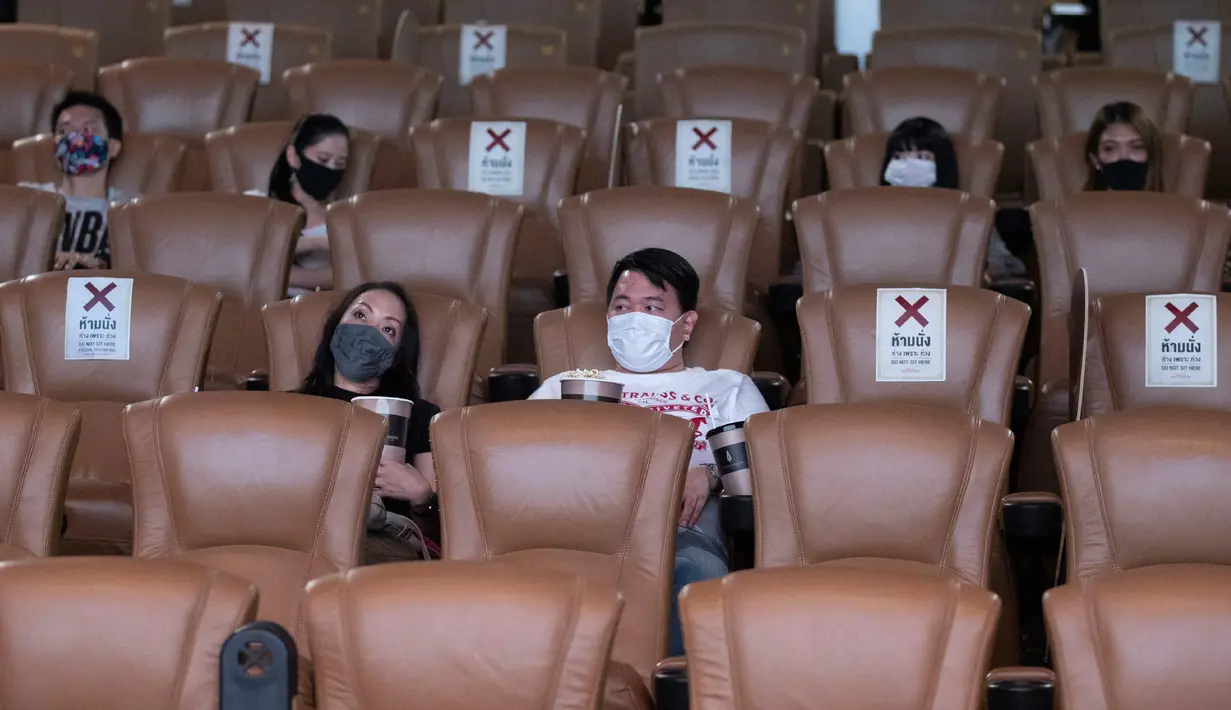 Pengunjung memakai masker duduk menjauh untuk mencegah penyebaran Covid-19 ketika mereka menonton film di bioskop Paragon Cineplex di Bangkok, Thailand, Senin (1/6/2020). (AP Photo/Sakchai Lalit)