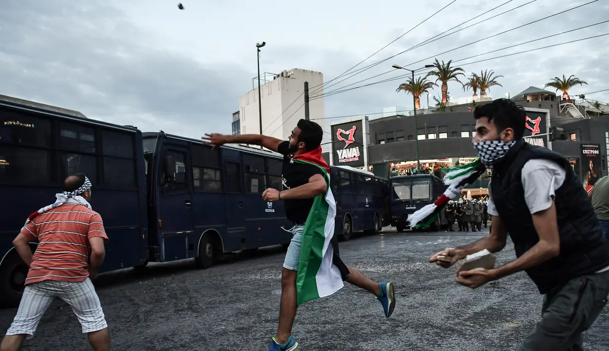 Pengunjuk rasa melempar batu ke kedutaan Israel pada unjuk rasa di Athena, Yunani, Selasa (15/5). Mereka mengecam tentara Israel menembak mati puluhan warga Palestina di perbatasan Gaza yang berunjuk rasa menentang pembukaan kedubes AS (AFP/Aris MESSINIS)