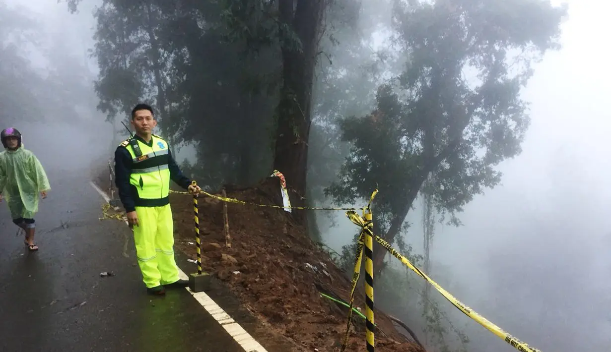Petugas dari kepolisian berjaga di lokasi longsor yang terjadi di kawasan Puncak Bogor, Jawa Barat (6/2). Menurut Kepala Polres Bogor Ajun Komisaris Besar AM Dicky, tiga orang korban di lokasi Riung Gunung belum ditemukan. (Liputan6.com/Pool/Polres Bogor)