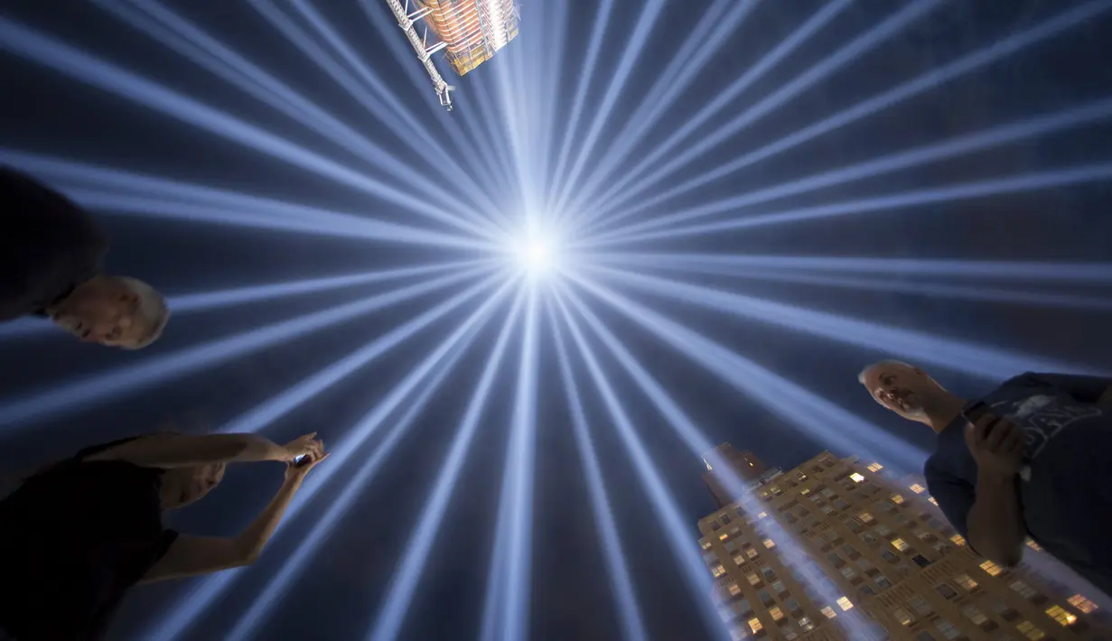 Pengunjung menikmati keindahan lampu sorot di World Trade Center (WTC) dipancarkan ke langit kota New York, AS, (9/9/2015). Acara dinamakan Tribute in Light memperingati 14 tahun tragedi terorisme 11 September di Amerika Serikat. (REUTERS/Andrew Kelly)