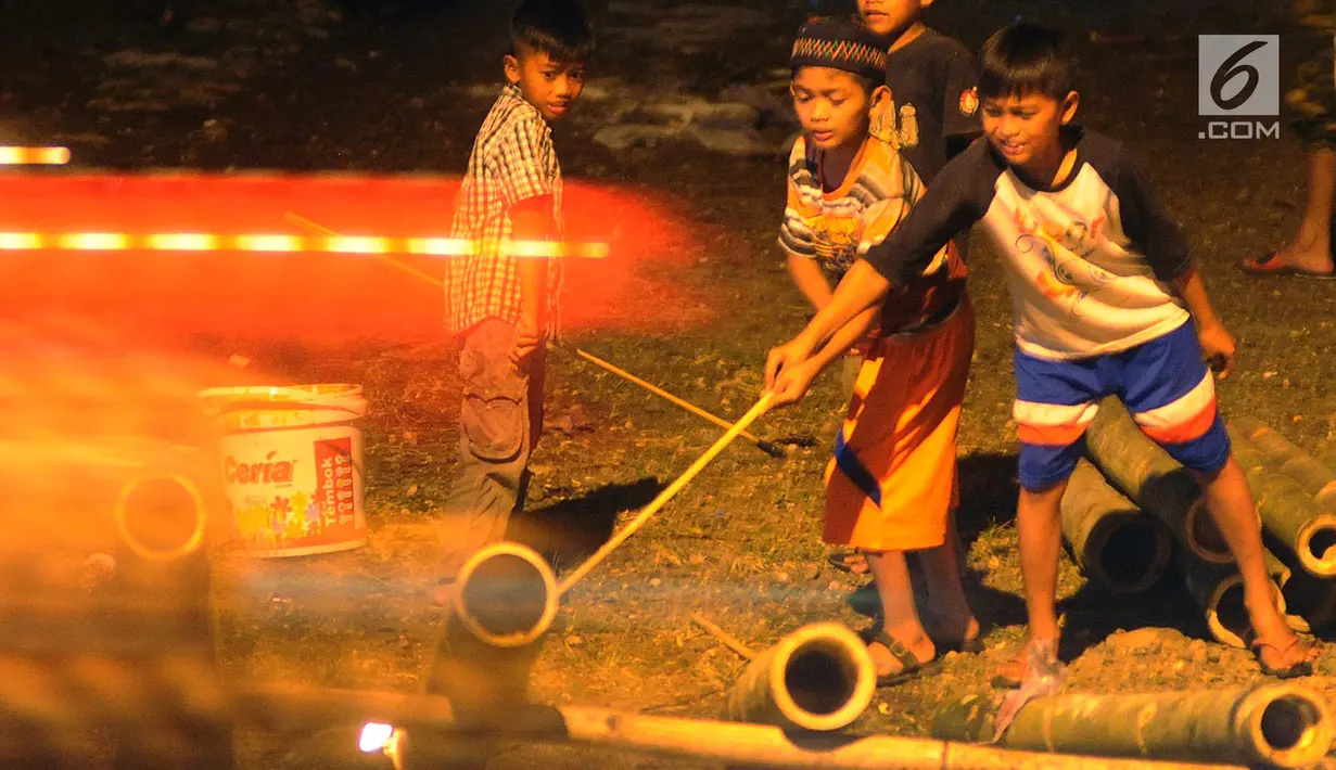 Anak-anak bermain meriam bambu atau bledugan saat merayakan malam takbiran di kawasan Cijeruk, Bogor, Jawa Barat, Selasa (4/6/2019). Bledugan memanfaatkan karbit yang dimasukkan ke dalam meriam bambu untuk kemudian diledakkan. (merdeka.com/Arie Basuki)