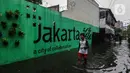 Seorang remaja melintasi banjir yang merendam lingkungan rumah tempat tinggal mereka di kawasan kecamatan Kebayoran Baru, Jakarta, Senin (25/01/2021). Hujan deras yang mengguyur Jakarta hari ini, Senin (25/1) menyebabkan terjadinya banjir di kawasan permukiman tersebut. (Liputan6.com/Johan Tallo)
