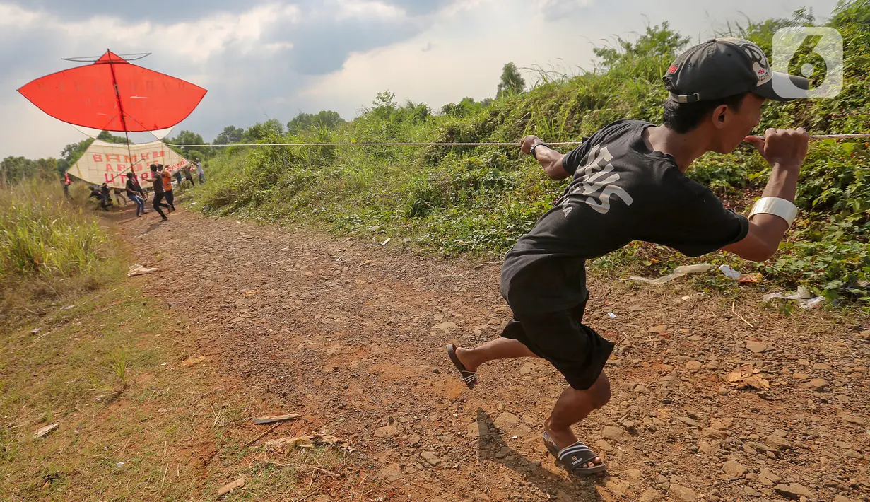 Warga menerbangkan layang-layang merah putih raksasa di kawasan Bambu Apus, Tangerang Selatan, Senin (17/8/2020). Layangan dengan bahan bambu, kertas dan plastik tersebut diterbangkan dalam rangka memperingati HUT Ke-75 RI. (Liputan6.com/Fery Pradolo)