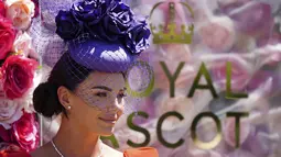 Seorang penonton wanita mengenakan topi bunga berpose untuk foto pada hari pertama acara balap kuda Royal Ascot, di Ascot Racecourse, di Ascot, Inggris, Selasa (14/6/2022). (AP Photo/Alastair Grant)