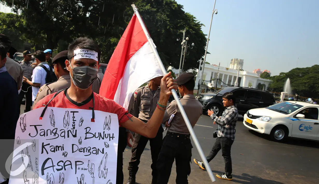 Seorang mahasiswa Riau Jabodetabek membawa bendera merah putih saat unjuk rasa di depan Istana Merdeka, Jakarta, Jumat (18/9/2015). Mereka menuntut penegakan hukum hingga tuntas pelaku pembakaran. (Liputan6.com/Faizal Fanani)