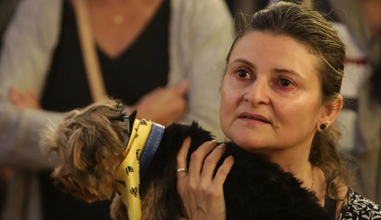 Salah satu jemaah membawa anjing peliharaannya saat Misa Santo Fransiskus berlangsung di Brasil, Rabu (4/10). Pemberkatan dengan cara hewan-hewan tersebut mendapat percikan air suci yang dilakukan oleh pastor  (AP Photo/Eraldo Peres)