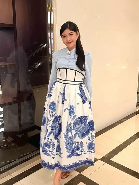 <p>Erina Gudono tampil mengenakan rok high waist warna putih dengan aksen batik ikan floral waena biru. Dipadukan dengan kemeja lengan panjang baby blue dan bros di bagian kerah. Ia pun memadukan dengan sandal Hermes warna coklat. [@erinagudono]</p>