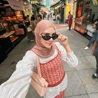 Syahnaz Sadiqah tampaknya konsisten berhijab. Gayanya saat ini dipuji makin cantik dan adem saat dilihat, termasuk potret yang satu ini. Ia tampil mengenakan set atasan tanpa lengan dan celana knitted bernuansa merah-oranye, dipadukan dengan oversized atasan putih sebagai inner, dan hijab cokelat yang serasi. [Foto: Instagram/syahnazs]