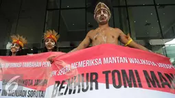 Sejumlah pemuda Papua mengenakan pakaian adat membentangkan spanduk di depan Gedung KPK, Jakarta, Senin (19/12). Mereka meminta KPK mengusut kasus korupsi pejabat yang mencalonkan diri pada Pilkada Jayapura 2017. (Liputan6.com/Helmi Affandi)