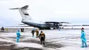Petugas medis menyambut kedatangan warga yang turun dari pesawat militer di sebuah bandara luar Tyumen, Rusia, Rabu (5/2/2020). Seluruh warga yang dievakuasi dari Wuhan menyusul wabah virus corona tersebut akan dikarantina selama dua minggu di Siberia. (AP Photo/Maxim Slutsky)