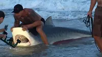 Seorang prajurit membuat kaget pengunjung pantai setelah menangkap hiu yang berenang dengan tangan kosong