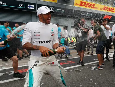 Pembalap Mercedes, Lewis Hamilton menyemprotkan sampanye saat merayakan keberhasilannya memenangkan GP Italia di Sirkuit Monza di Monza, Italia, (2/9). Saat ini Hamilton menempati urutan pertama klasemen dengan 231 poin. (AP Photo/Antonio Calanni)