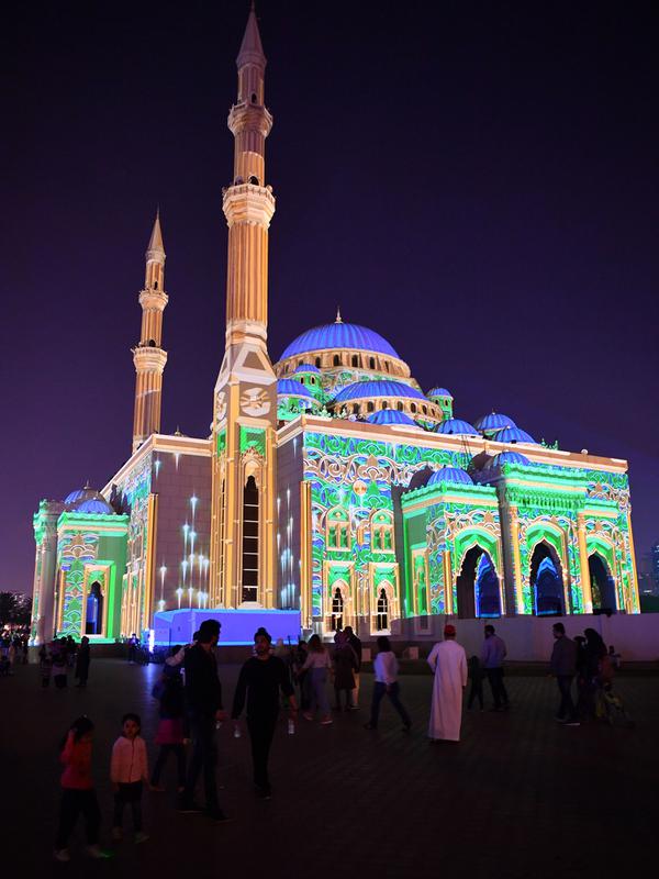 Pengunjung berada di depan Masjid Al-Noor yang diterangi lampu warna-warni selama Festival Cahaya Sharjah di Uni Emirat Arab pada 7 Februari 2020. Festival yang sudah memasuki tahun kesepuluh ini selalu sukses memikat wisatawan lokal maupun asing. (Photo by GIUSEPPE CACACE / AFP)