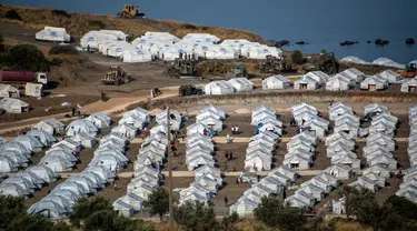 Alat berat beroperasi saat para migran berkumpul di kamp tenda sementara di Kara Tepe, Lesbos, Yunani, Kamis (17/9/2020). Lebih dari 5.000 pencari suaka kehilangan tempat tinggal sepekan setelah kebakaran menghanguskan kamp migran terbesar di Yunani, Kamp Moria. (AP Photo/Panagiotis Balaskas)