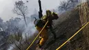 Seorang pemadam kebakaran sedang memanjat bukit untuk memadamkan api, California, AS, Senin (3/8/2015). Sedikitnya 9.000 petugas damkar berjuang mengatasi sebanyak 18 kebakaran hutan yang melanda Negara Bagian California, AS. (Reuters/ Stephen Lam) 