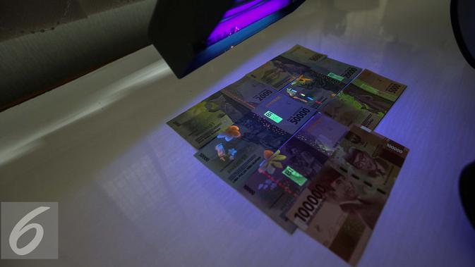 Gambar uang kertas rupiah disinari lampu ultraviolet di kantor Peruri, Karawang, Jawa Barat, Rabu (18/1). Rupiah memiliki sistem pengamanan tiga level dan menjadi mata uang yang pengamanannya sangat kompleks. (Liputan6.com/Faizal Fanani)